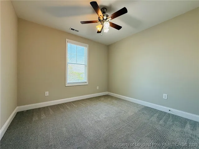 an empty room with a window and a fan
