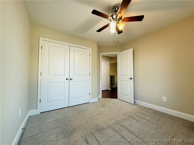 an empty room with closet and a ceiling fan