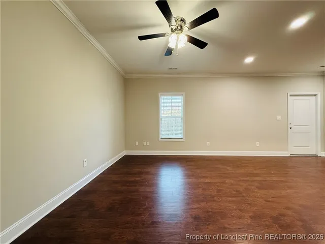 an empty room with wooden floor and a ceiling fan