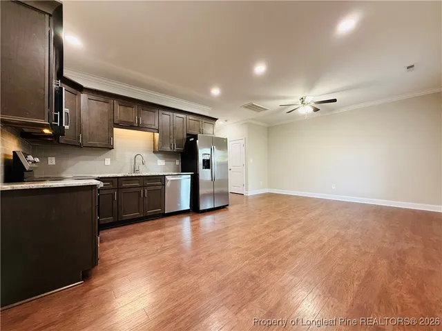 a kitchen with kitchen island granite countertop stainless steel appliances and wooden cabinets