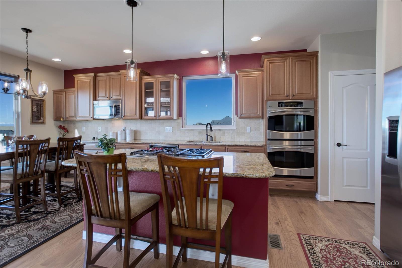 3441 Antelope Ridge Trail Parker, CO 80138 - Photo 14 of 50 a kitchen with stainless steel appliances granite countertop a stove a refrigerator a kitchen island a dining table and chairs