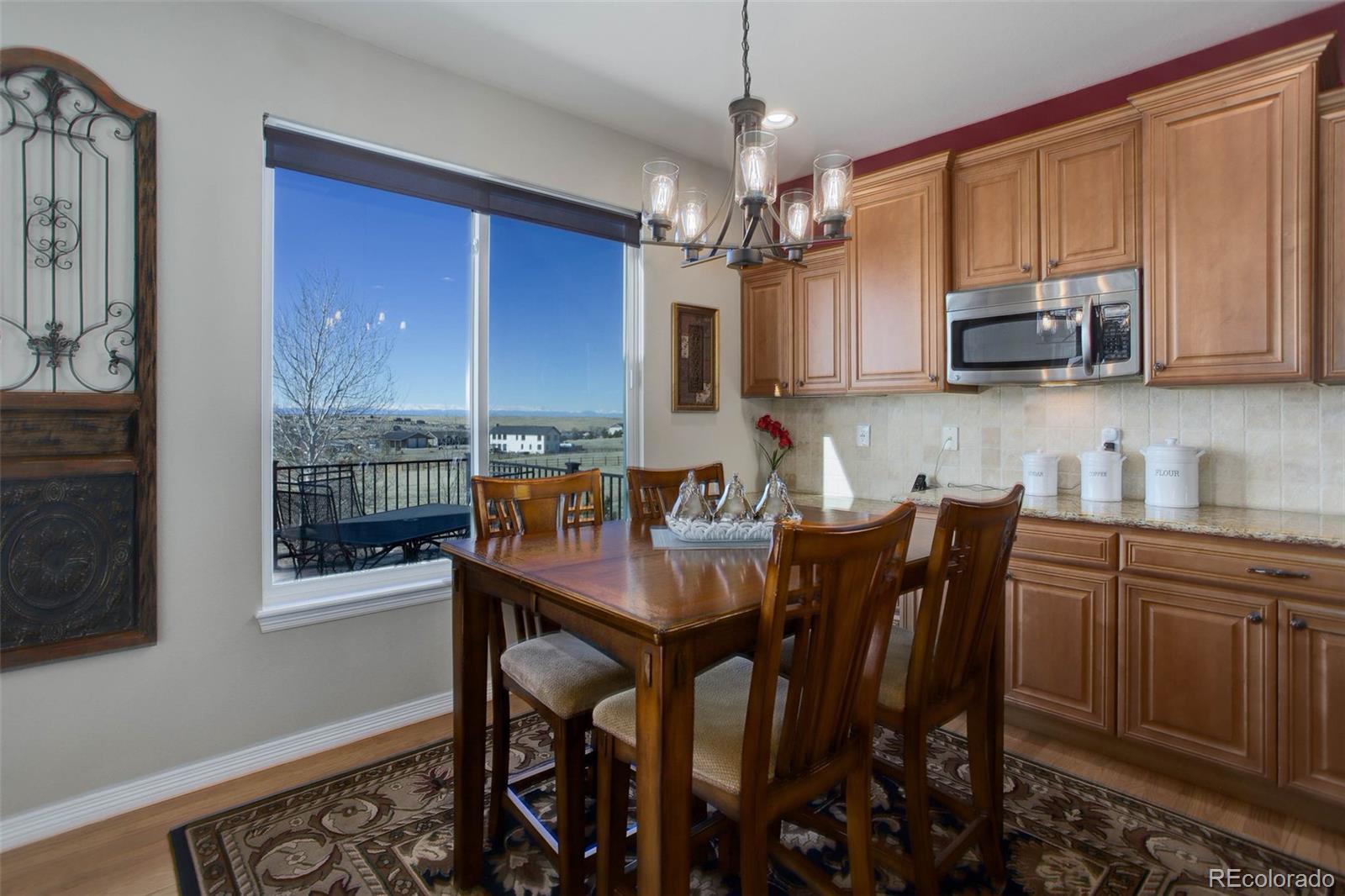 3441 Antelope Ridge Trail Parker, CO 80138 - Photo 18 of 50 a kitchen with stainless steel appliances granite countertop a stove top oven a sink dishwasher a dining table and chairs with wooden floor