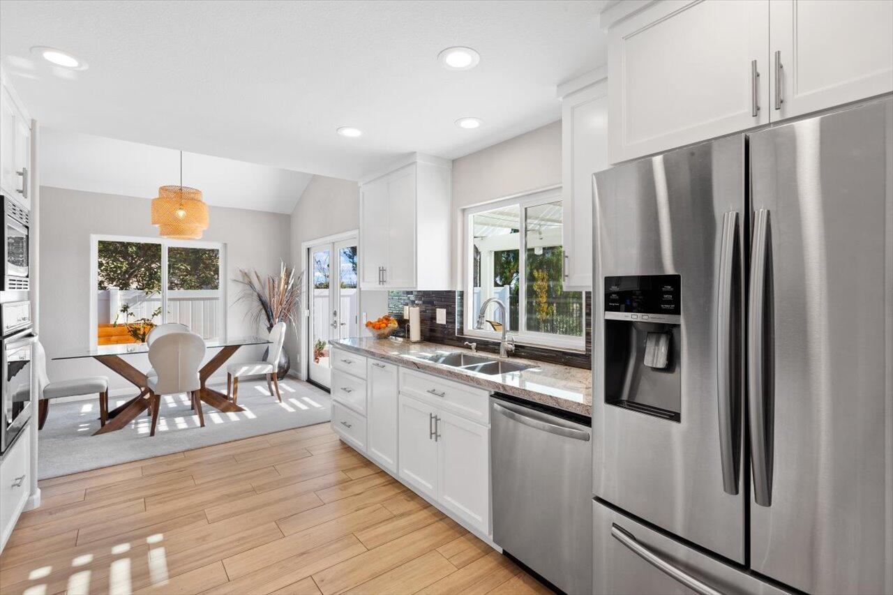 911 Rivertree Drive Oceanside, CA 92058 - Photo 9 of 43 a kitchen with stainless steel appliances a refrigerator a stove a sink a dining table and chairs