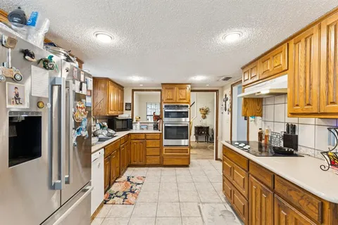 a kitchen with stainless steel appliances granite countertop a stove top oven a sink dishwasher and cabinets with wooden floor