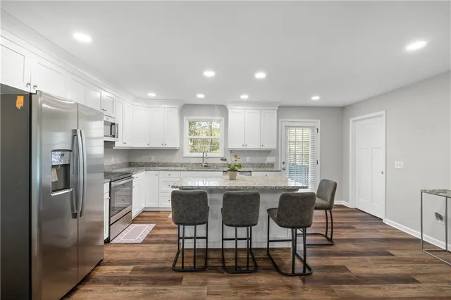 a kitchen with kitchen island granite countertop wooden floors granite counter tops and white appliances