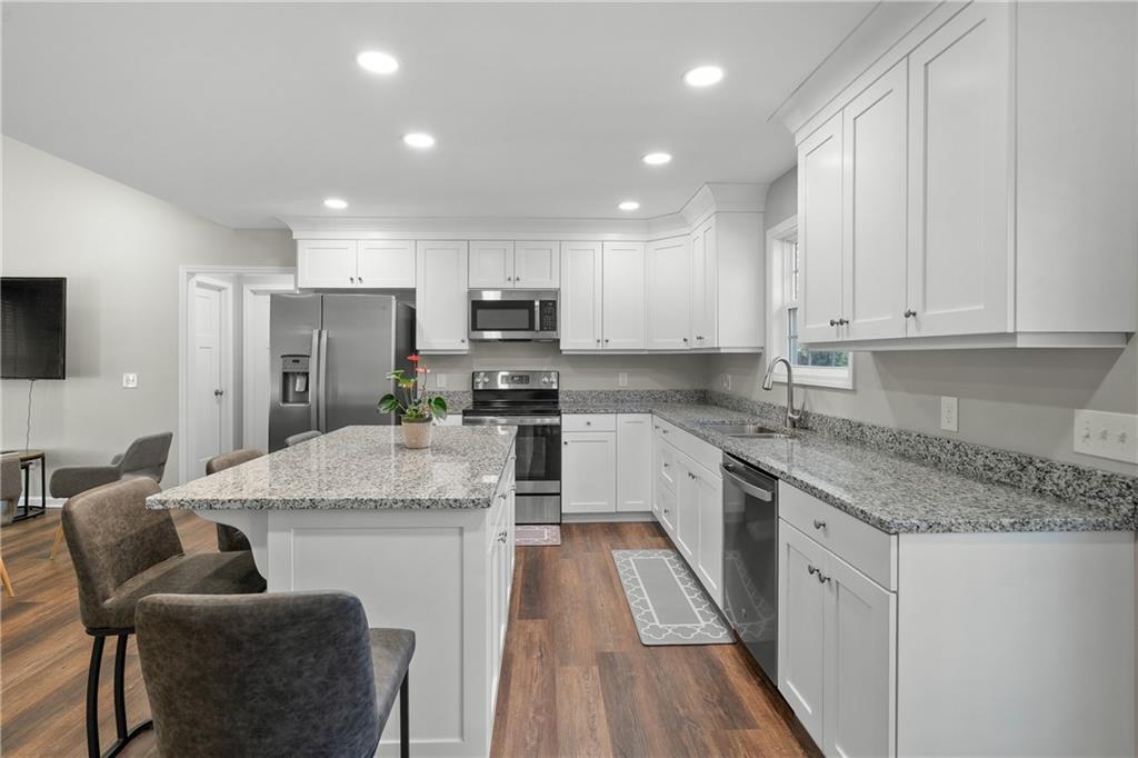 2708 Quarles Road Rocky Face, GA 30740 - Photo 19 of 40 a kitchen with kitchen island granite countertop wooden floors granite counter tops and white appliances