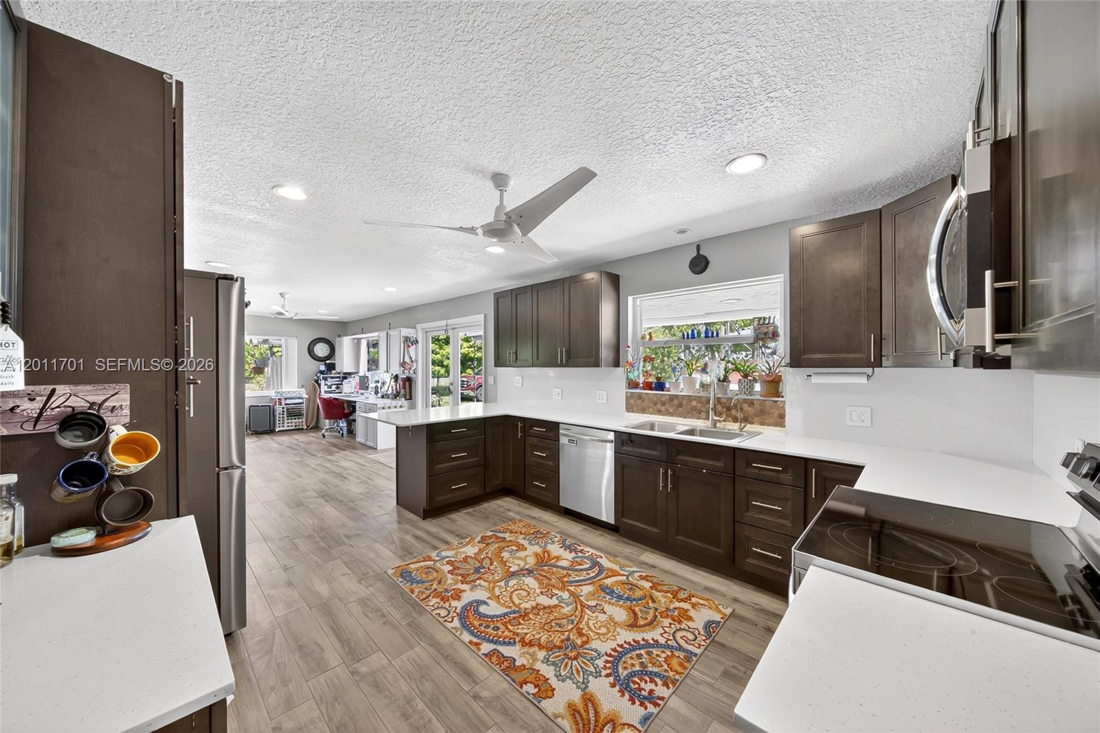 21175 Southwest 232nd Street Miami, FL 33170 - Photo 12 of 66 a large white kitchen with a stove a sink dishwasher and a fireplace with wooden floor