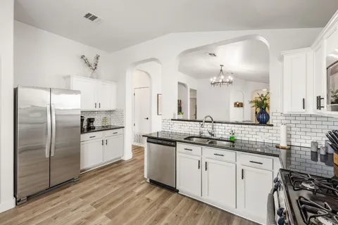 a kitchen with stainless steel appliances a sink cabinets and wooden floor