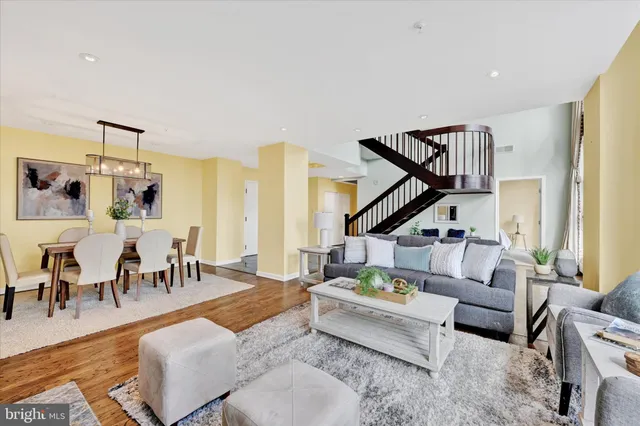 a living room with furniture and a dining table with wooden floor