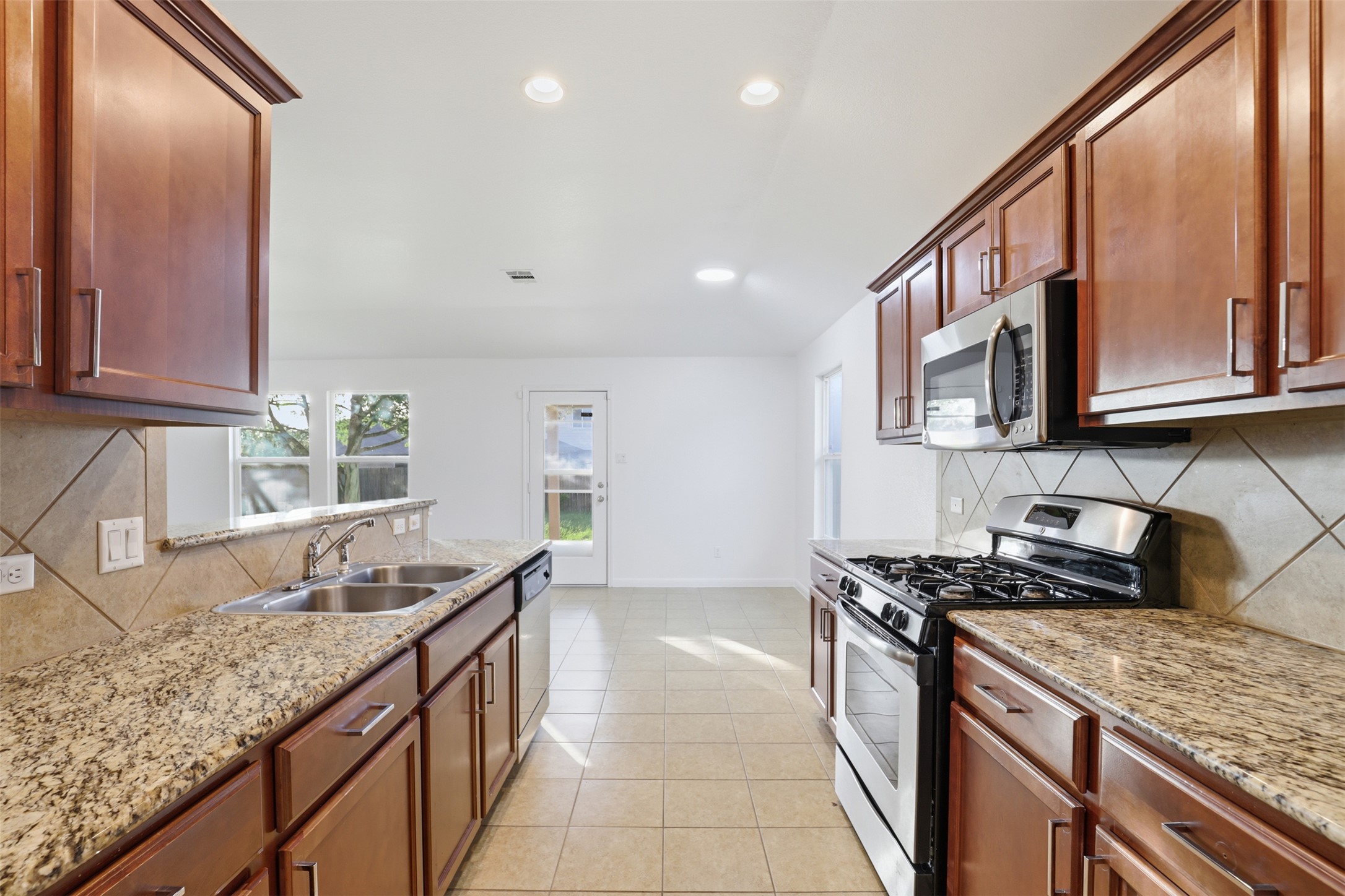 448 Nottingham Loop Kyle, TX 78640 - Photo 2 of 16 Gourmet kitchen featuring granite countertops, wood cabinetry, stainless steel appliances, a double basin sink, and tile flooring