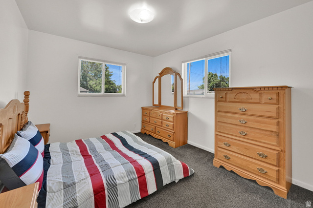 2467 South 2000 West Syracuse, UT 84075 - Photo 5 of 28 Bright room featuring two windows with white trim, dark carpeting, and a flush-mount ceiling light fixture