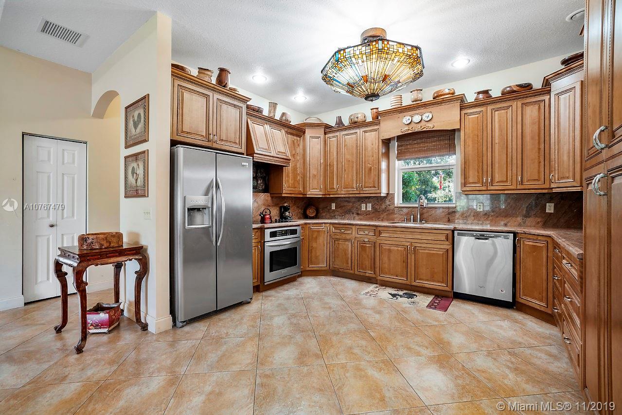 6915 Southwest 185th Way Southwest Ranches, FL 33332 - Photo 25 of 48 a kitchen with granite countertop a stove a sink dishwasher a refrigerator and cabinets with wooden floor