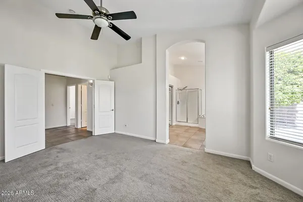 an empty room with windows and a ceiling fan