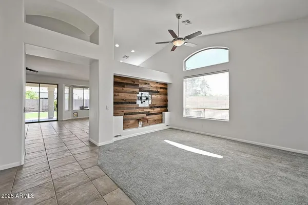 a view of an empty room with window and chandelier fan
