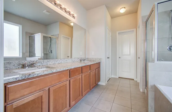 a bathroom with a granite countertop bathtub shower sink and mirror