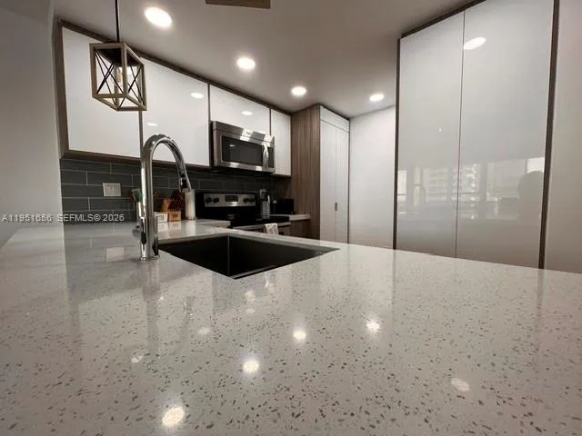 a kitchen with stainless steel appliances a sink a stove a microwave a sink and cabinets