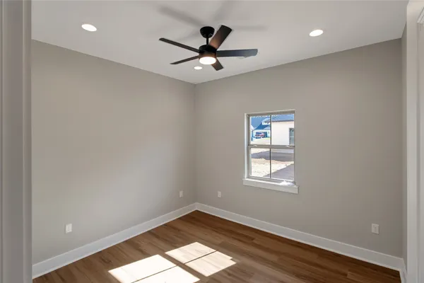 a view of empty room with wooden floor and fan