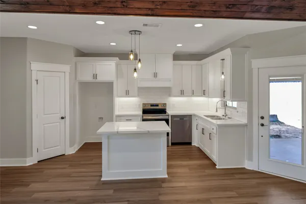 a large kitchen with cabinets wooden floor and stainless steel appliances