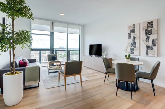 a living room with furniture floor to ceiling window and a flat screen tv