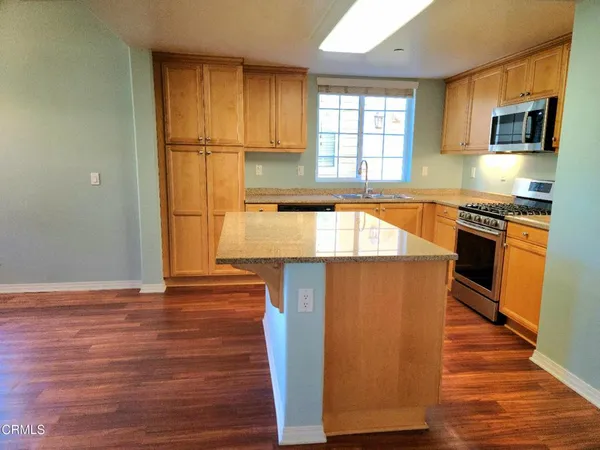 a kitchen with stainless steel appliances granite countertop a refrigerator a stove top oven a sink and dishwasher with wooden floor