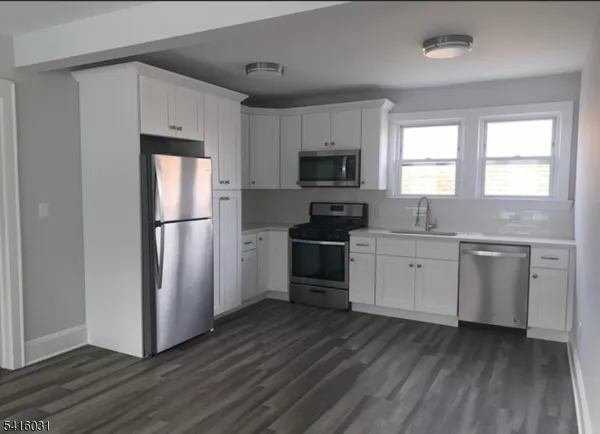 a kitchen with a refrigerator wooden floor a stove a sink and a window