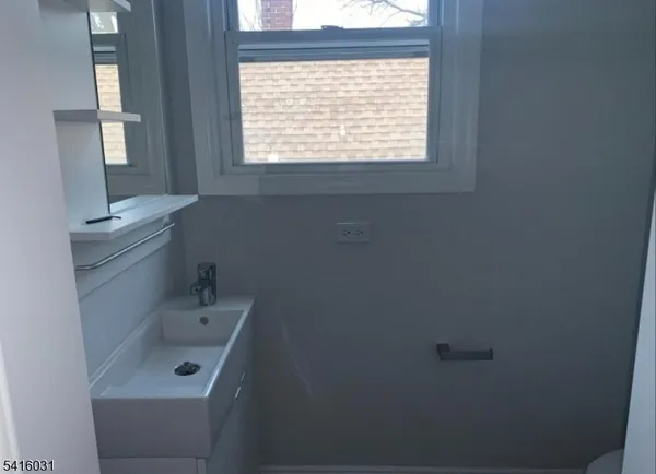 a bathroom with a sink a window and a toilet