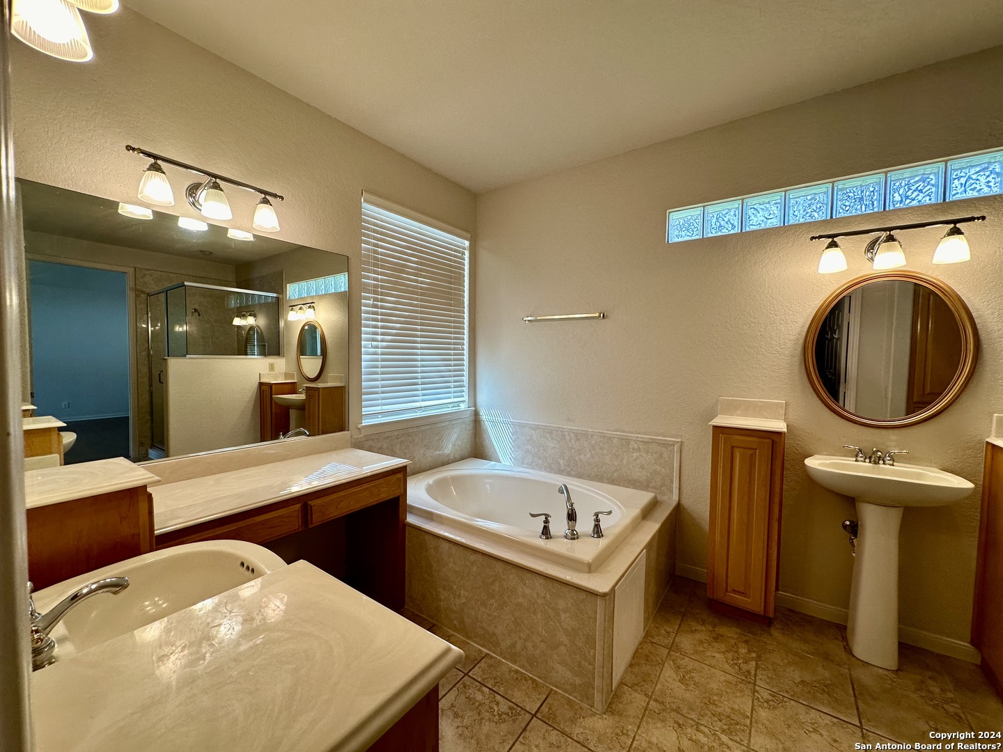 23107 Osprey Ridge San Antonio, TX 78258 - Photo 21 of 28 a bathroom with a sink a mirror and a bathtub