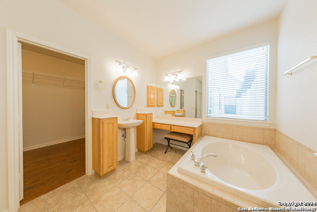 23107 Osprey Ridge San Antonio, TX 78258 - Photo 24 of 28 a bathroom with a tub sink and a mirror