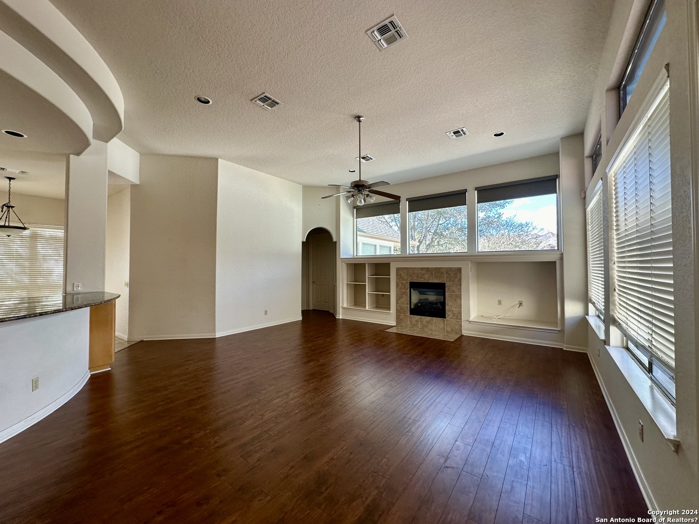 23107 Osprey Ridge San Antonio, TX 78258 - Photo 6 of 28 an empty room with wooden floor fireplace and windows