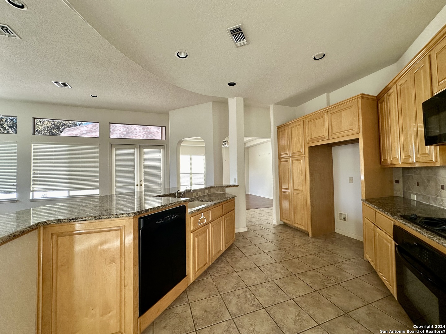 23107 Osprey Ridge San Antonio, TX 78258 - Photo 8 of 28 a large kitchen with kitchen island granite countertop a large window and stainless steel appliances