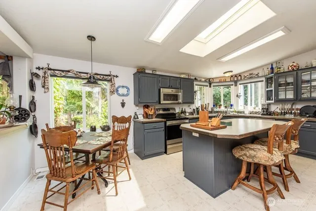 a kitchen with kitchen island a large counter top space appliances and a window