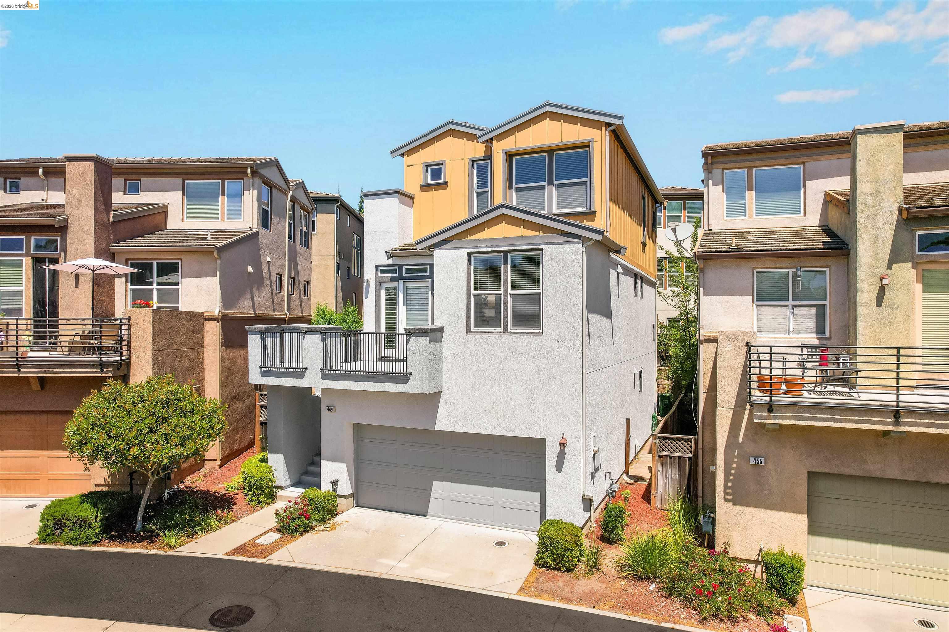 449 Constantine Court San Ramon, CA 94583 - Photo 5 of 63 Modern townhouse featuring a light gray stucco exterior with wood-tone accents, an attached garage, and a private balcony with dark gray railings