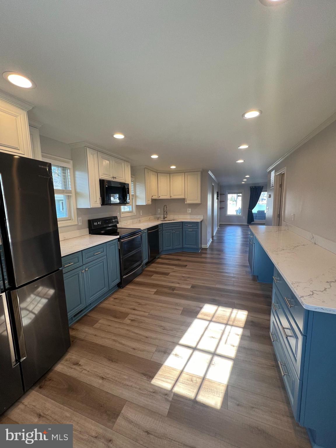 1890 Locust Road Pasadena, MD 21122 - Photo 44 of 53 a large kitchen with kitchen island granite countertop a refrigerator a stove a sink a washer dryer and a dining table with wooden floor
