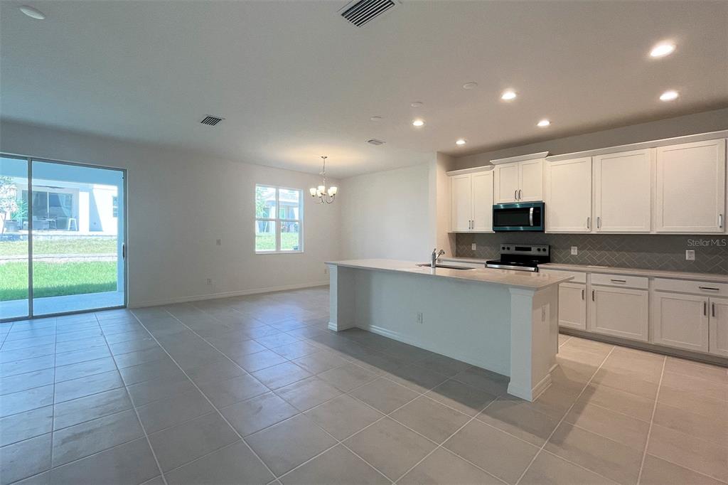 7036 Rolling Leaf Road Groveland, FL 34736 - Photo 3 of 18 a kitchen with stainless steel appliances granite countertop a stove a sink and a refrigerator