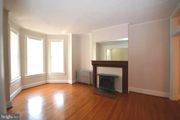 an empty room with wooden floor fireplace and windows