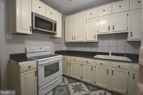 a kitchen with granite countertop white cabinets white stainless steel appliances and a sink