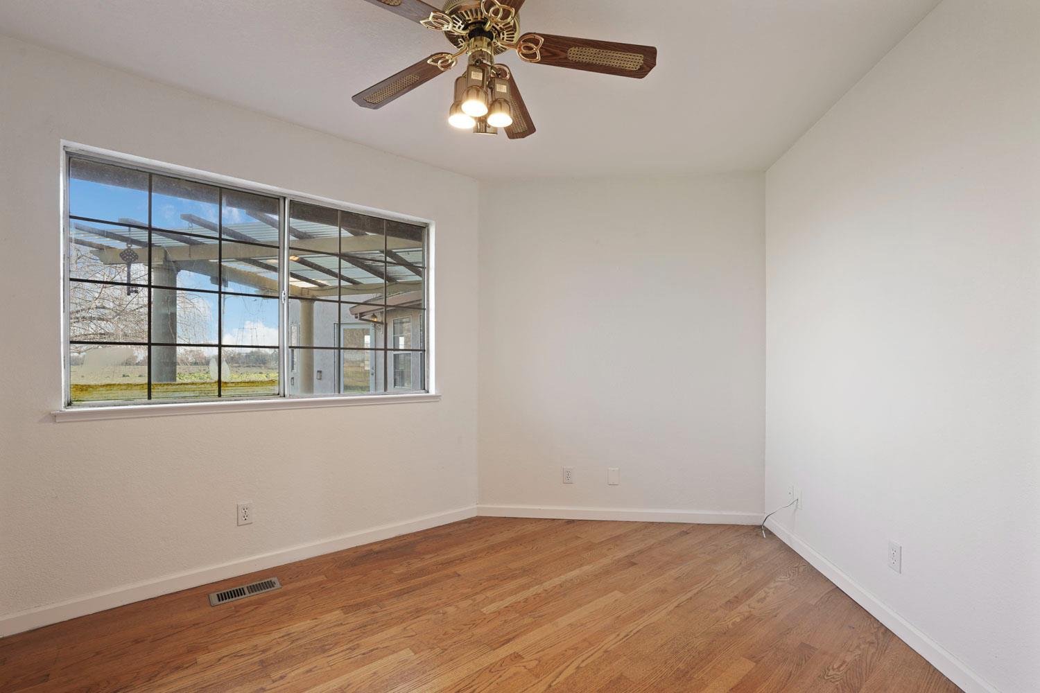 16321 South Wing Levee Road Stockton, CA 95206 - Photo 35 of 71 an empty room with wooden floor chandelier fan and windows