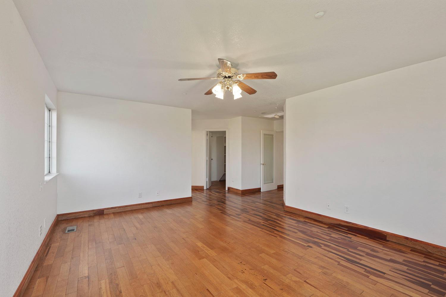 16321 South Wing Levee Road Stockton, CA 95206 - Photo 40 of 71 a view of an empty room with wooden floor and a ceiling fan