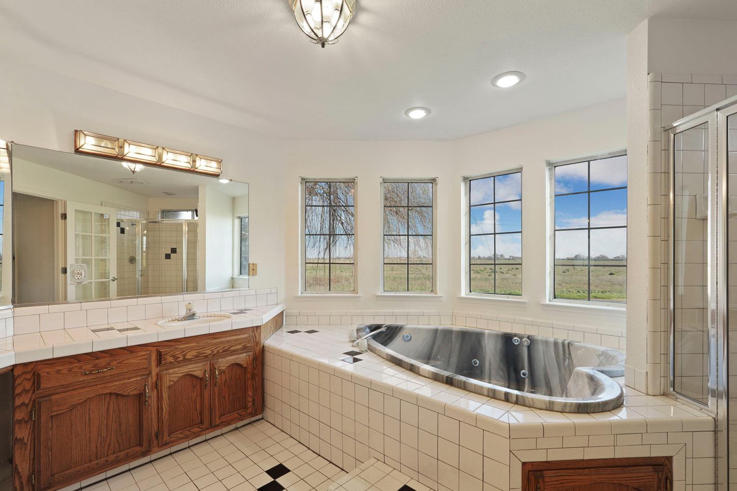 16321 South Wing Levee Road Stockton, CA 95206 - Photo 42 of 71 a bathroom with a granite countertop tub a sink a mirror and a shower