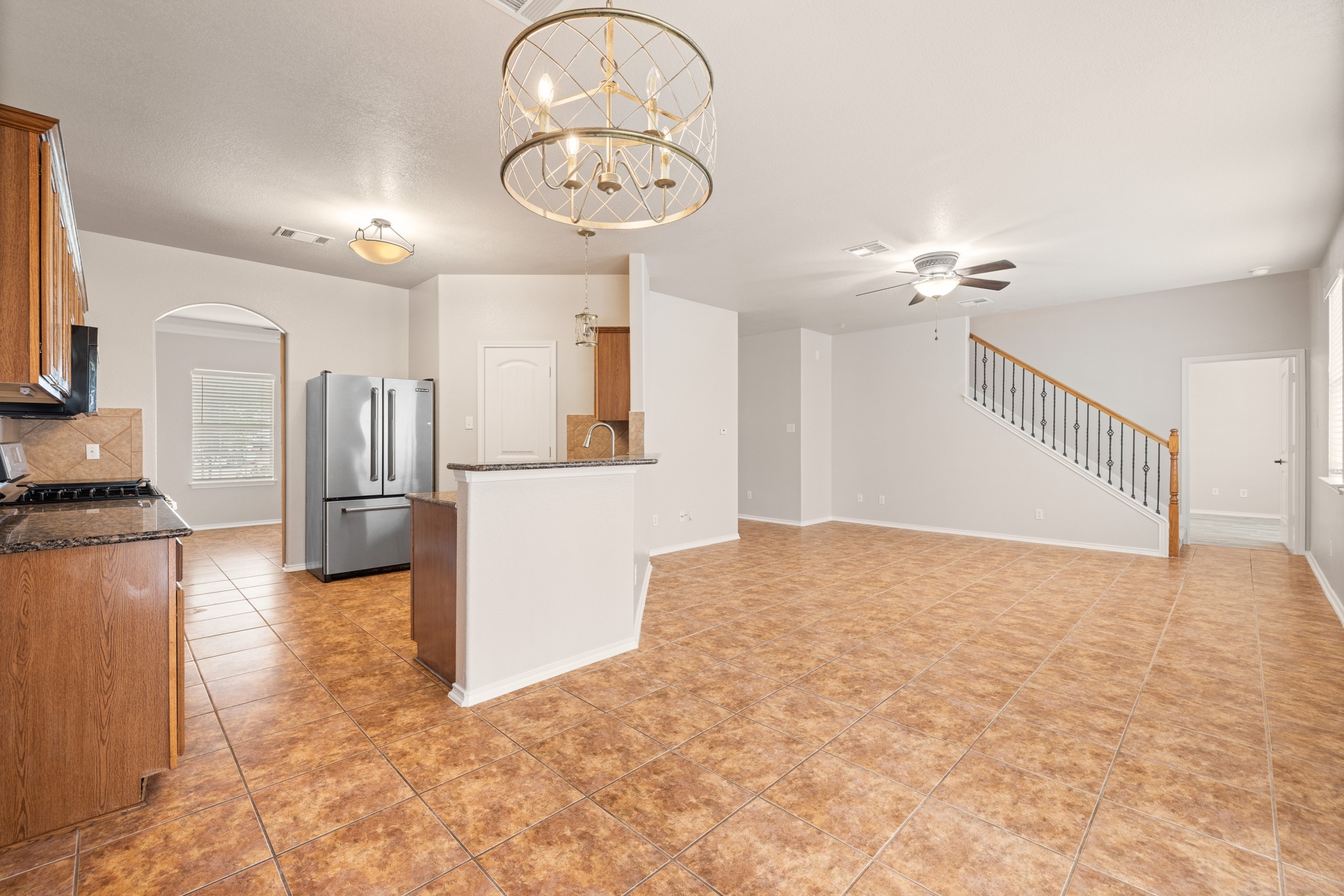403 Red Hawk Drive Leander, TX 78641 - Photo 10 of 37 Open-concept living area featuring tile flooring, a staircase with wood railing and wrought iron spindles, and a ceiling fan