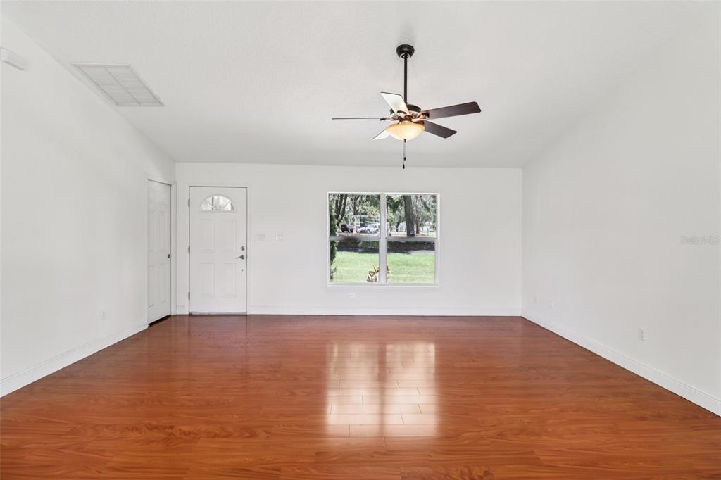 40610 Babb Road Umatilla, FL 32784 - Photo 10 of 45 an empty room with wooden floor chandelier fan and windows