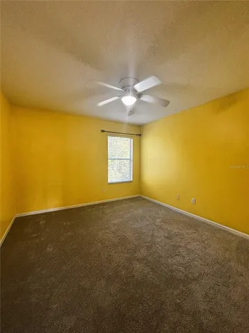 a view of an empty room with a ceiling fan and window