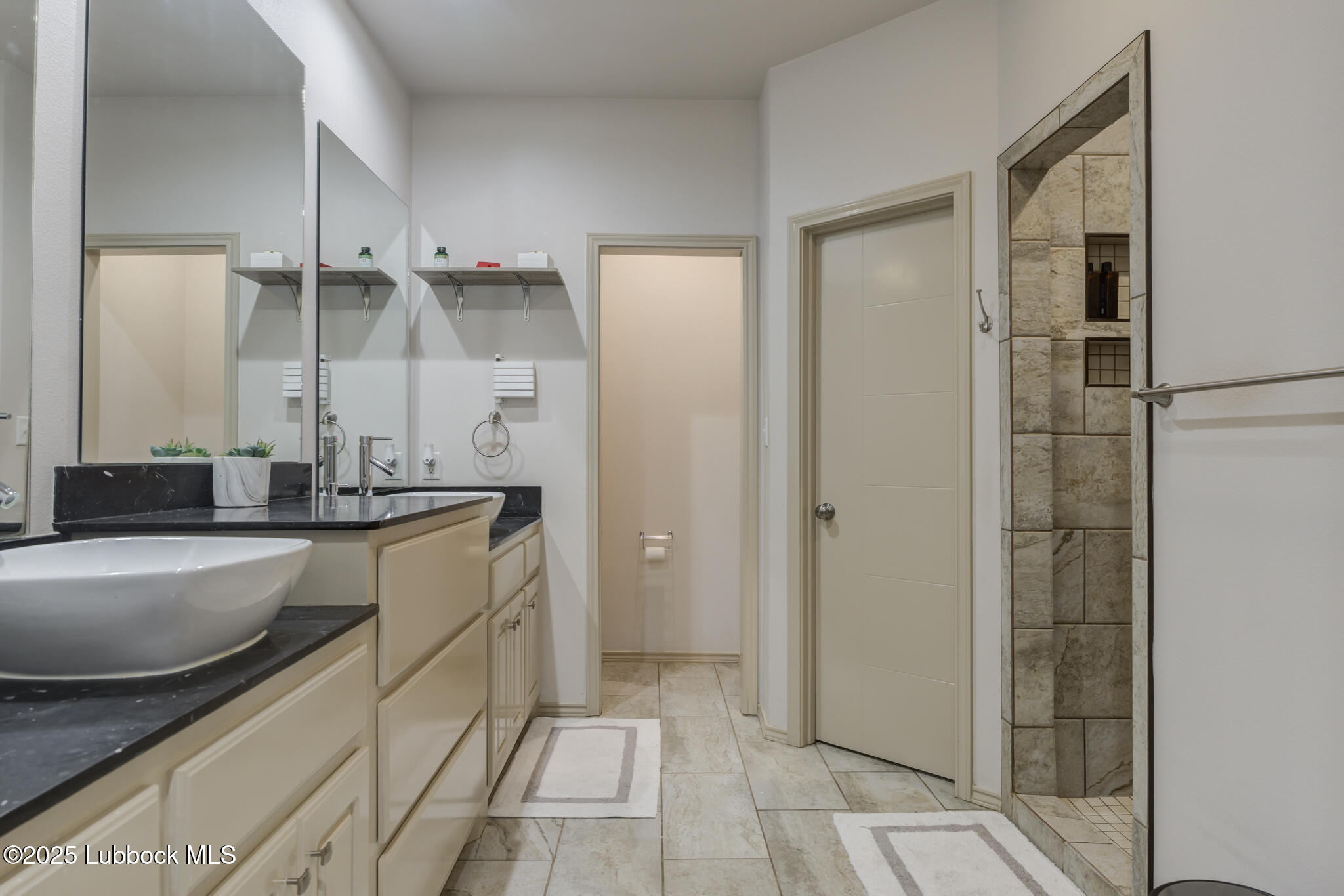 5218 Lehigh Street Lubbock, TX 79416 - Photo 27 of 39 a spacious bathroom with a granite countertop sink a mirror and shower