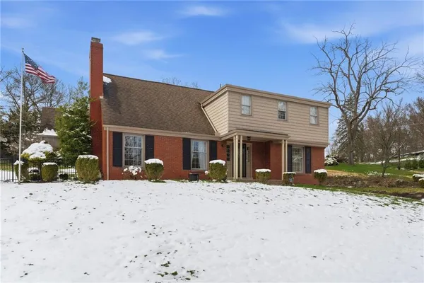 a front view of a house with a yard covered with snow