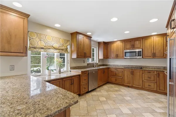 a kitchen with granite countertop a stove a sink a oven a dining table and chairs