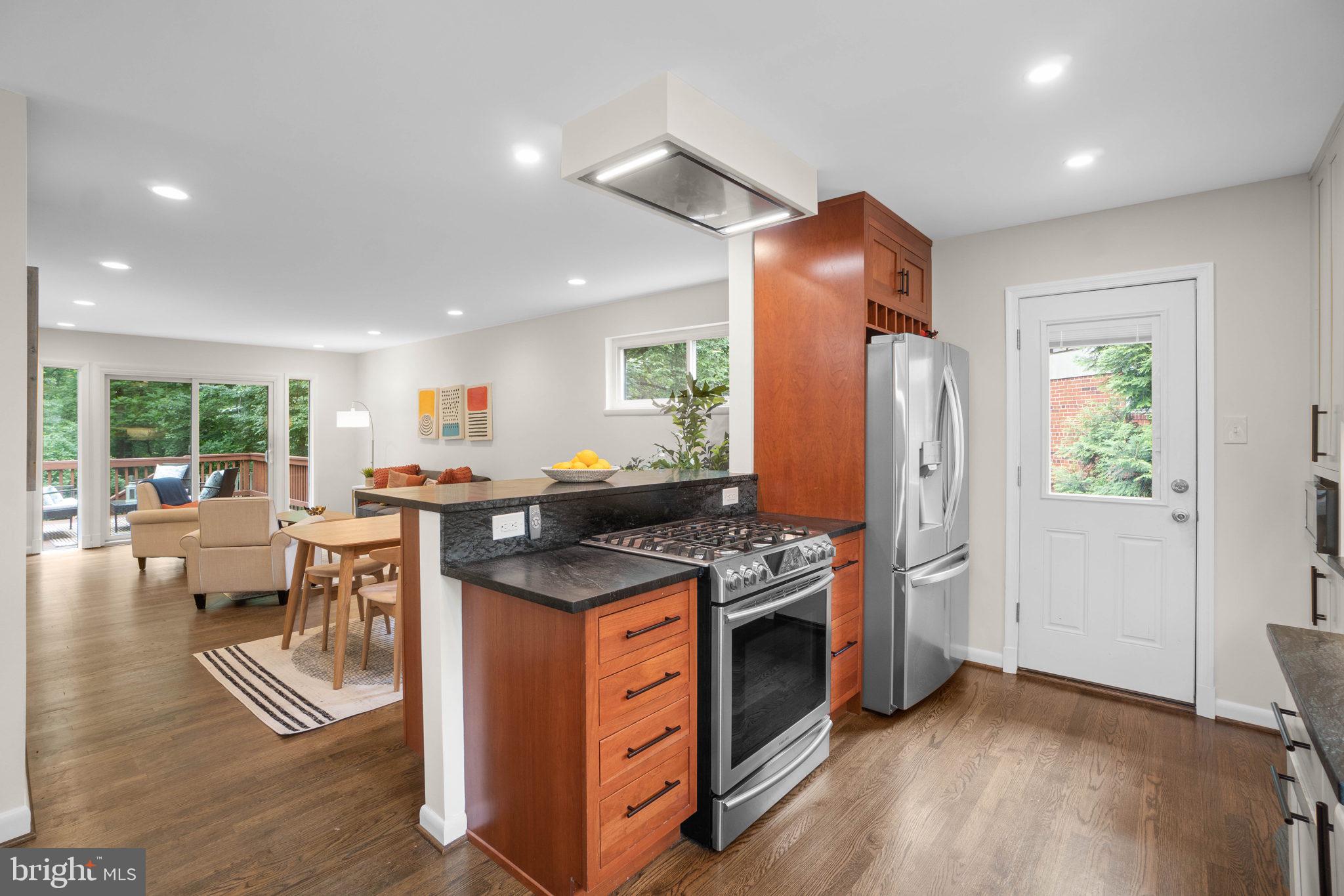 a kitchen with stainless steel appliances granite countertop a stove refrigerator and a dining table with wooden floor