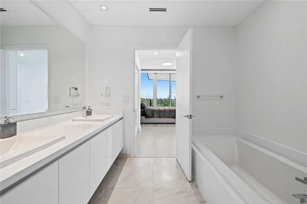 a spacious bathroom with a tub sink and mirror