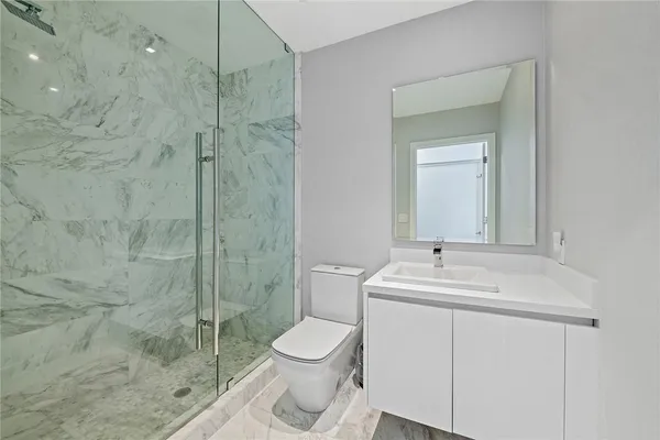 a bathroom with a toilet sink vanity and shower
