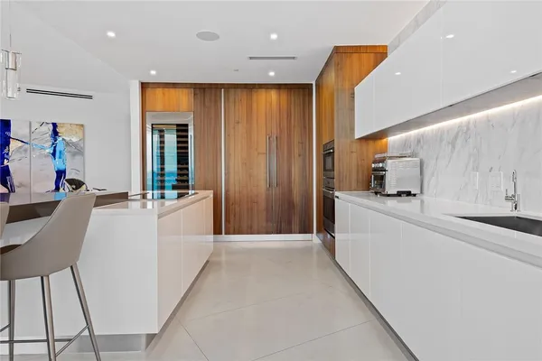 a large white kitchen with cabinets a sink and a refrigerator