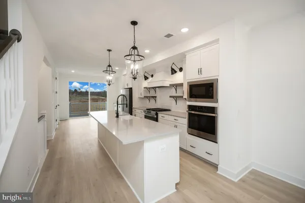 a large kitchen with stainless steel appliances kitchen island a large counter top a stove and a chandelier
